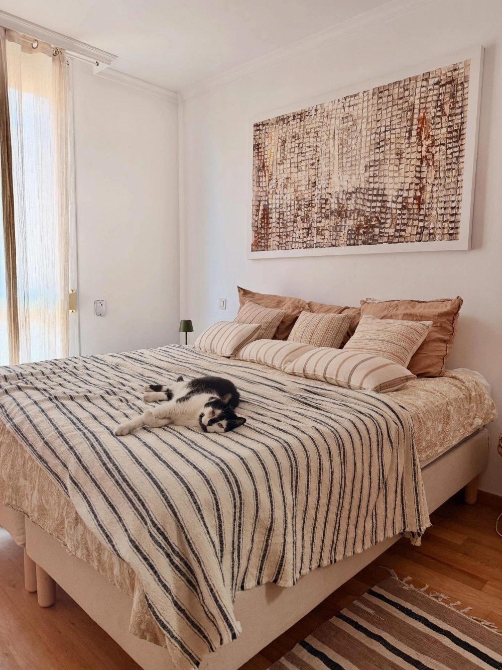 Màu sơn phòng ngủ màu trắng sáng giúp làm nổi bật tranh treo tường khổ lớn và nội thất đơn giản